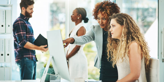 Woman points out something on a screen to coworker