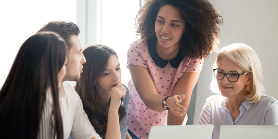 employees discussing content while looking at laptop