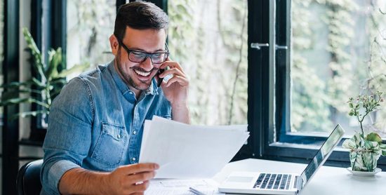 engaged employee speaking on the phone wile reading papers