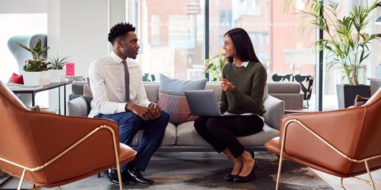 Businesswoman Interviewing Male Job Candidate In Seating Area Of Modern Office