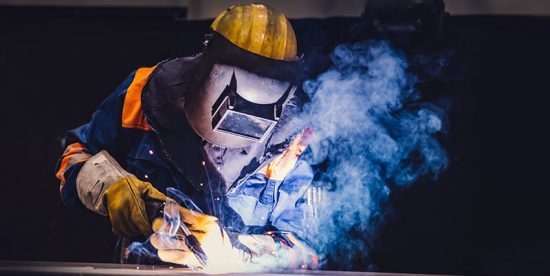 Blue-collar worker welds in a factory.