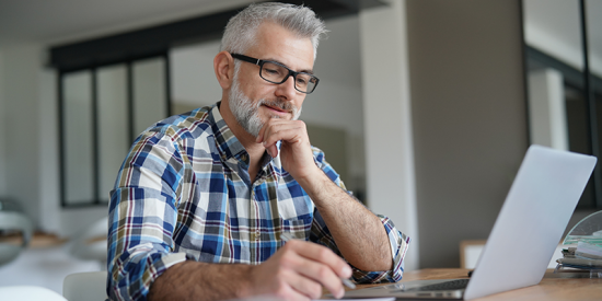 Instructional designer sits at desk and looks at computer.