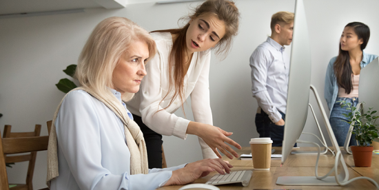 Younger worker explains a task to frustrated Boomer employee.