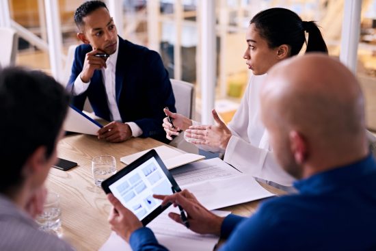 coworkers in a meeting discussing information on a tablet