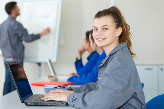 female blue-collar apprentice using laptop in classroom